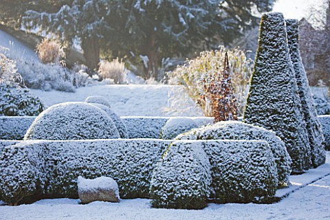 PETTIFERS__OXFORDSHIRE_GARDEN_IN_SNOW_IN_WINTER__THE_PARTERRE_IN_WINTER_WITH_CLIPPED_BOX_AND_YEW_SCU