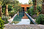 DESIGNERS ERIC OSSART AND ARNAUD MAURIERES  MOROCCO: AL HOSSOUN - COURTYARD AROUND THE MAIN POOL/CANAL REFLECTING A SOLANUM  PALM AND AGAVE DESMETTIANA