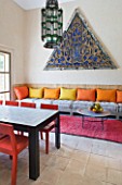 DESIGNERS ERIC OSSART AND ARNAUD MAURIERES  MOROCCO: AL HOSSOUN - LIVING ROOM WITH ORANGE AND YELLOW CUSHIONS ON SETTEE