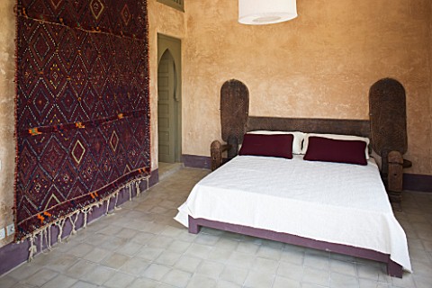 DESIGNERS_ERIC_OSSART_AND_ARNAUD_MAURIERES__MOROCCO_AL_HOSSOUN__BEDROOM_WITH_WOODN_BED__MAGENTA_CUSH