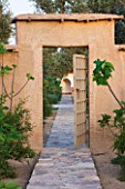 DESIGNERS ERIC OSSART AND ARNAUD MAURIERES  MOROCCO: DAR IGDAD - PATH TO GATE IN EARTH WALL - ORCHARD WITH FIG TREES