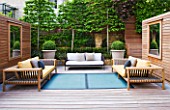 ROOF GARDEN DESIGNED BY STEPHEN WOODHAMS  LONDON: DECKING  WOODEN FURNITURE WITH CUSHIONS  MIRRORS ON WOODEN PANELS  BOX BALLS IN CONTAINERS