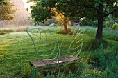 MOORS MEADOW GARDEN AND NURSERY  HEREFORDSHIRE: THE WINGED SEAT BY DAVE BISSELL AT DAWN ON THE EDGE OF THE OAK CIRCLE