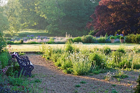 NARBOROUGH_HALL_GARDENS__NORFOLK_THE_GRAVELO_GARDEN_WITH_METAL_BENCH_SEAT_AT_THE_FRONT_OF_THE_HOUSE