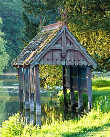 NARBOROUGH_HALL_GARDENS__NORFOLK_THE_RECENTLY_RESTORED__LISTED_BOAT_HOUSE_ON_THE_BANKS_OF_THE_RIVER_