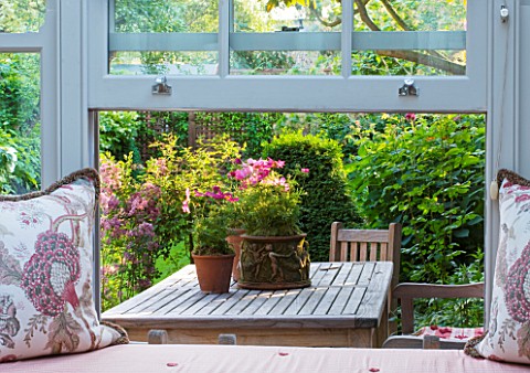 DESIGNER_BUTTER_WAKEFIELD__LONDON_VIEW_OUT_OF_CONSERVATORY_WITH_CUSHIONS_BY_DRAGON_FLOWER_TO_TERRACE