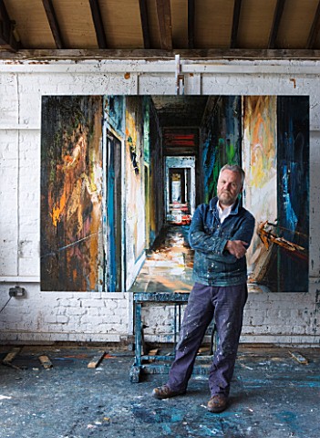 THE_HOUSE_OF_JOHN_AND_SUE_MONKS__LONDON_JOHN_IN_HIS_STUDIO_BESIDE_AN_OIL_PAINTING