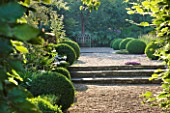 SANDHILL FARM HOUSE  HAMPSHIRE - DESIGNER ROSEMARY ALEXANDER - WIDE GRAVEL PATH EDGED WITH CLIPPED BOX LEADING TO A METAL SEAT IN THE FRONT GARDEN