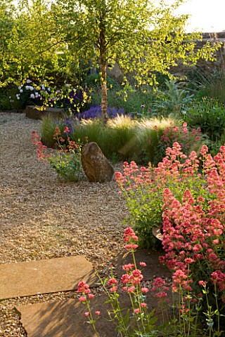 RICKYARD_BARN_GARDEN__NORTHAMPTONSHIRE_GRAVEL_GARDEN_WITH_STONE_SCULPTURE_AND_CENTRANTHUS_RUBER__RED