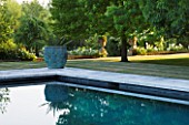 PRIVATE GARDEN, COTSWOLDS: DESIGNER ALISON HENRY - LAWN, SWIMMING POOL, BRONZE CONTAINER WITH CORDYLINE. FORMAL, WATER, CLASSIC,  ENGLISH,  GARDEN
