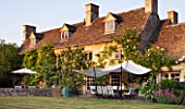 DESIGNER ALISON HENRY, PRIVATE GARDEN, COTSWOLDS - THE HOUSE WITH LAWN, STONE TERRACE / PATIO WITH SEATS AND CANVAS SAIL CANOPY - COUNTRY, GARDEN, SUMMER, CLASSIC, ENGLISH
