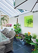 DESIGNER CLARE MATTHEWS: CONSERVATORY WITH WICKER TABLE AND CHAIRS AND CONTAINERS