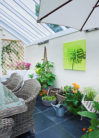 DESIGNER_CLARE_MATTHEWS_CONSERVATORY_WITH_WICKER_TABLE_AND_CHAIRS_AND_CONTAINERS