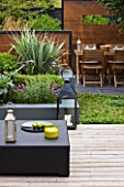 SMALL TOWN GARDEN  LONDON. DESIGNER - ANA SANCHEZ - MARTIN  OF GERMINATE DESIGN - WOODEN TABLE AND CHAIRS  SQUARE LANTERN  SCREENS MADE OF MILD STEEL  DECKING  RAISED BED