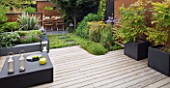 SMALL TOWN GARDEN  LONDON. DESIGNER - ANA SANCHEZ - MARTIN  OF GERMINATE DESIGN - WOODEN TABLE AND CHAIRS  SQUARE LANTERN  SCREENS MADE OF MILD STEEL  DECKING  RAISED BED