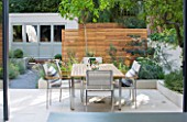 @JARDINROSAINSPIRATIONS - SMALL TOWN GARDEN: VIEW FROM KITCHEN TO WHITE PORCELAIN TILED DINING AREA/ PATIO.TABLE/CHAIRS - A PLACE TO SIT . BLUE SUMMERHOUSE IN BACKGROUND