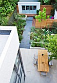 @JARDINROSAINSPIRATIONS - SMALL TOWN GARDEN: VIEW DOWN ONTO WHITE PORCELAIN TILED DINING AREA/ PATIO.TABLE AND CHAIRS - A PLACE TO SIT. PATH AND BLUE SUMMERHOUSE