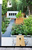 @JARDINROSAINSPIRATIONS - SMALL TOWN GARDEN: VIEW DOWN ONTO WHITE PORCELAIN TILED DINING AREA/ PATIO.TABLE AND CHAIRS - A PLACE TO SIT. PATH AND BLUE SUMMERHOUSE