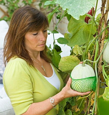 DESIGNER_CLARE_MATTHEWS_CLARE_HOLDS_A_NET_USED_TO_PACKAGE_AVACADOS_USED_AS_A_NET_TO_SUPPORT_A_SWEETH