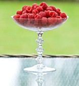 DESIGNER CLARE MATTHEWS: RASPBERRIES IN GLASS BOWL ON GLASS TOPPED TABLE