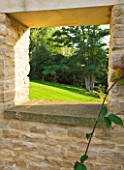 WHATLEY MANOR  WILTSHIRE: SQUARE HOLE IN VEGETABLE / KITCHEN/ POTAGER GARDEN WALL WITH VIEW TO COUNTRYSIDE BEYOND