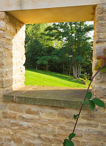 WHATLEY_MANOR__WILTSHIRE_SQUARE_HOLE_IN_VEGETABLE__KITCHEN_POTAGER_GARDEN_WALL_WITH_VIEW_TO_COUNTRYS