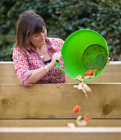 DESIGNER_CLARE_MATTHEWS_FRUIT_GARDEN_PROJECT__CLARE_COMPOSTING_WITH_A_GREEN_BUCKET_FULL_OF_VEGETABLE