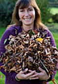DESIGNER: CLARE MATTHEWS: FRUIT GARDEN PROJECT - CLARE HOLDING DRY BROWN LEAVES FOR COMPOSTING