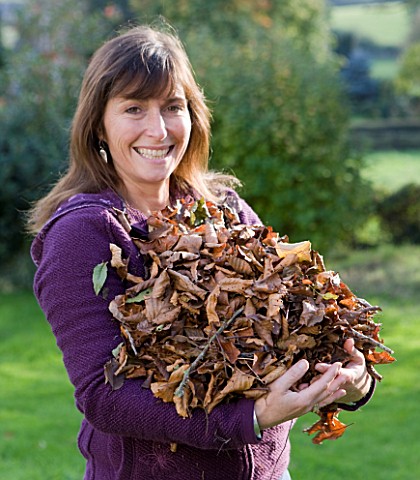 DESIGNER_CLARE_MATTHEWS_FRUIT_GARDEN_PROJECT__CLARE_HOLDING_DRY_BROWN_LEAVES_FOR_COMPOSTING