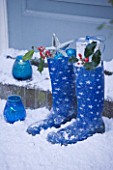 HIGHFIELD HOLLIES  HAMPSHIRE. FRONT DOOR WITH SNOW AND BLUE BOOTS WITH HOLLY. BLUE CANDLES
