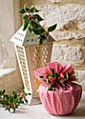 DESIGNER - JACKY HOBBS : CHRISTMAS DECORATION - CANDLE IN LANTERN   CHRISTMAS PUDDING WRAPPED IN RED AND WHITE CHECKED CLOTH AND HOLLY BERRIES AND LEAVES  IN WINDOWSILL