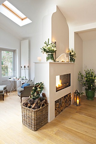 DESIGNER_JACKY_HOBBS__LONDON_LIVING_ROOM_AT_CHRISTMAS__TWO_SIDED_FIREPLACE_WITH_WOOD_BASKET