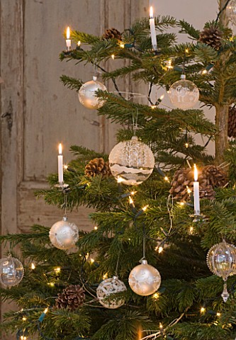 DESIGNER_JACKY_HOBBS__LONDON_LIVING_ROOM_AT_CHRISTMAS__CHRISTMAS_TREE_WITH_CANDLES__PINE_CONES_AND_B