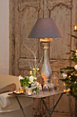 DESIGNER: JACKY HOBBS  LONDON - CHRISTMAS - TABLE WITH GLASS JARS  CANDLES AND LAMP  IN LIVING ROOM