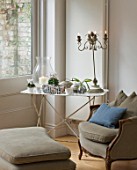 DESIGNER: JACKY HOBBS  LONDON - CHRISTMAS - WHITE METAL TABLE WITH GLASS CANDLE HOLDER  CYCLAMEN IN CONTAINERS  AND LAMP  IN LIVING ROOM