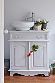 DESIGNER: JACKY HOBBS  LONDON: BATHROOM AT CHRISTMAS WITH CYCLAMEN AND HOLLY