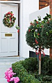 DESIGNER: JACKY HOBBS  LONDON: CHRISTMAS - FRONT GARDEN - CANDLE HOLDER OUTSIDE WITH HOLLY DECORATION  CYCLAMEN IN CONTAINERS  WREATH ON FRONT DOOR