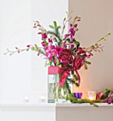 DESIGNER: JACKY HOBBS  LONDON: THE LIVING ROOM AT CHRISTMAS WITH FLOWERS IN GLASS VASES ON MANTELPIECE