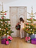 DESIGNER: JACKY HOBBS  LONDON: JACKY IN THE LIVING ROOM AT CHRISTMAS WITH DOOR  WREATH AND TWO CHRISTMAS TREES WITH PRESENTS