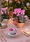 DESIGNER: JACKY HOBBS  LONDON: THE LIVING ROOM AT CHRISTMAS WITH DINING TABLE SET WITH PINK CYCLAMEN IN CONTAINERS