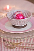 DESIGNER: JACKY HOBBS  LONDON: THE LIVING ROOM AT CHRISTMAS WITH DINING TABLE SET WITH PINK DECORATIVE BAUBLES IN BOWL