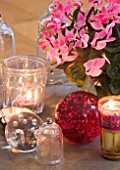 DESIGNER: JACKY HOBBS  LONDON: THE LIVING ROOM AT CHRISTMAS WITH DINING TABLE SET WITH GLASS BALLS  CANDLES AND PINK CYCLAMEN IN A CONTAINER