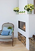 DESIGNER: JACKY HOBBS  LONDON: THE LIVING ROOM AT CHRISTMAS WITH FIRE AND POINSETTIAS IN WHITE CONTAINERS ON FIREPLACE MANTELPIECE. HOUSEPLANTS