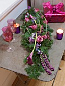 DESIGNER: JACKY HOBBS  LONDON: THE LIVING ROOM AT CHRISTMAS WITH FLOWER BOUQUET  CANDLES  PRESENT AND WINE GLASSES ON METAL TABLE