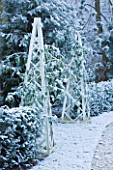 FORMAL TOWN GARDEN IN SNOW  OXFORD  WINTER: DESIGN BY LIZ NICHOLSON - PATH THROUGH GARDEN WITH WOODEN OBELISKS AND YEW HEDGING
