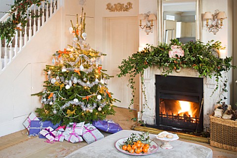 BRUERN_COTTAGES__OXFORDSHIRE_CHRISTMAS__THE_SITTING_ROOM_WITH_FIREPLACE__CHRISTMAS_TREE_AND_OTTOMAN_