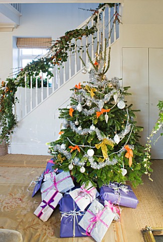 BRUERN_COTTAGES__OXFORDSHIRE_CHRISTMAS__THE_SITTING_ROOM_WITH_CHRISTMAS_TREE_WITH_PRESENTS_AND_STAIR