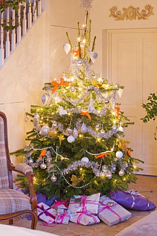 BRUERN_COTTAGES__OXFORDSHIRE_CHRISTMAS__THE_SITTING_ROOM_WITH_CHRISTMAS_TREE_SURROUNDED_BY_PRESENTS