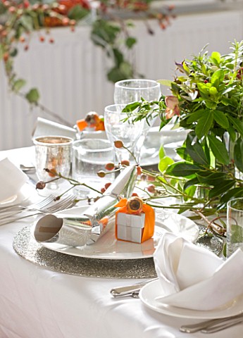 BRUERN_COTTAGES__OXFORDSHIRE_CHRISTMAS__PLACE_SETTING_WITH_CRACKER_AND_PRESENT_WRAPPED_IN_ORANGE_RIB