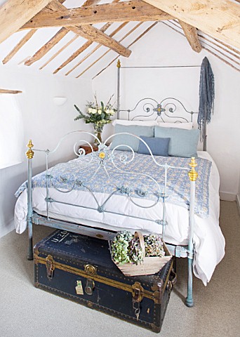 DESIGNER_CAROLYN_MINTY__GLOUCESTERSHIRE__GUEST_BEDROOM_WITH_IRON_BED_AND_VINTAGE_LEATHER_TRUNK